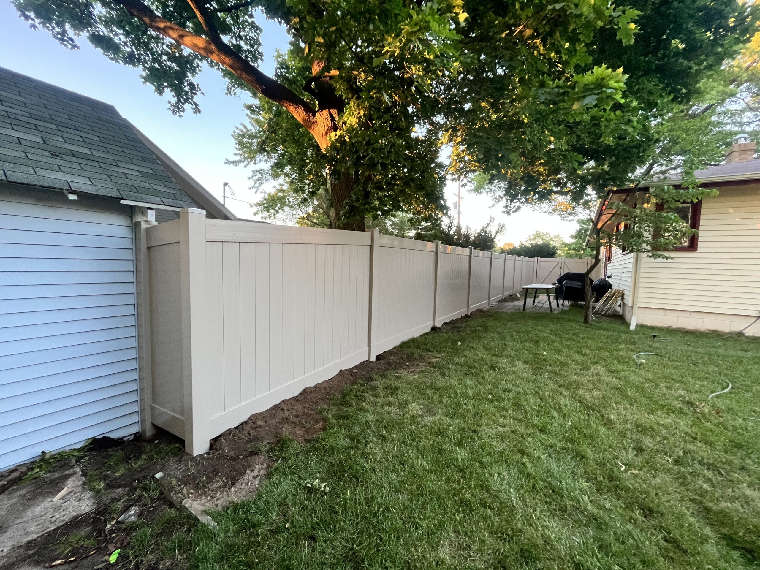 White vinyl privacy fence running along the side yard of a West Michigan home